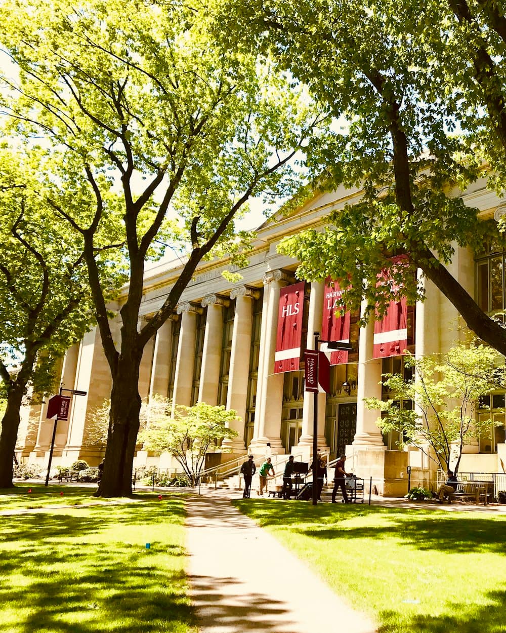 A university colonnade opening onto a lawn, banners hanging between the columns.